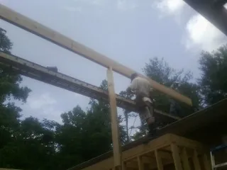Carpenter setting a ridge beam over a new addition frame — Ice Dam Removal by Roofing Brothers in Chanute