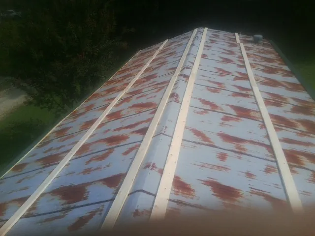 Rusted metal roof panels with new wood purlins before replacement — Storm Damage Roof Repair in Chanute by Roofing Brothers