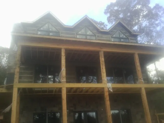 Dormers and porch framing on a large log home under construction — Roof Coating work by our crew in Chanute