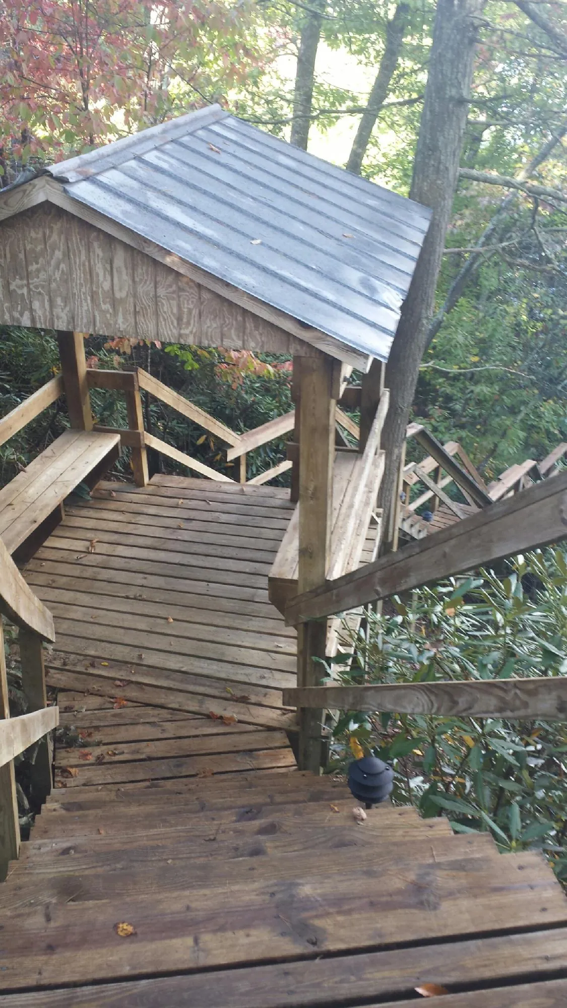 Metal roofed shelter over wooden steps on a wooded walkway — Skylight Repair & Installation work by our crew in Chanute