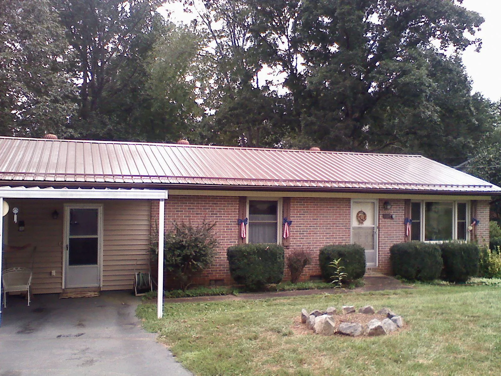 Bronze metal roof and carport on a brick ranch home — Roof Repair work by our crew in Chanute