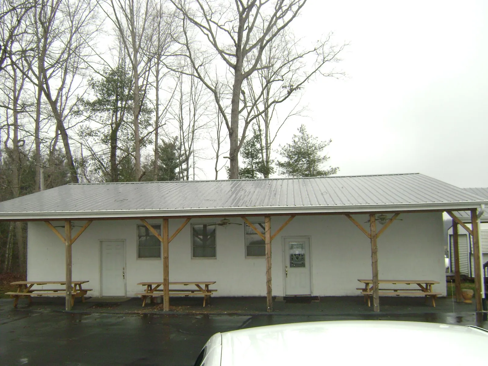 Gray metal roof over a block building with a timber post porch in Chanute