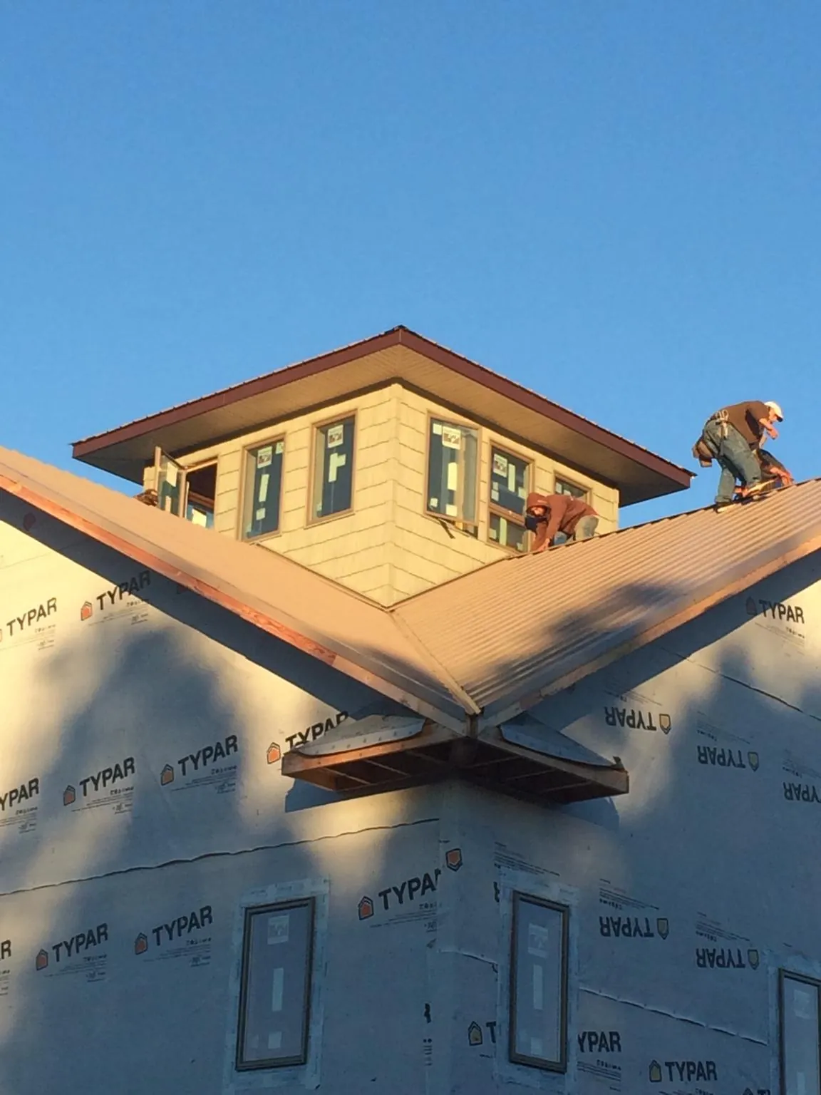 Roofers working around a rooftop cupola on a new metal roof at sunset — Roof Waterproofing in Chanute by Roofing Brothers